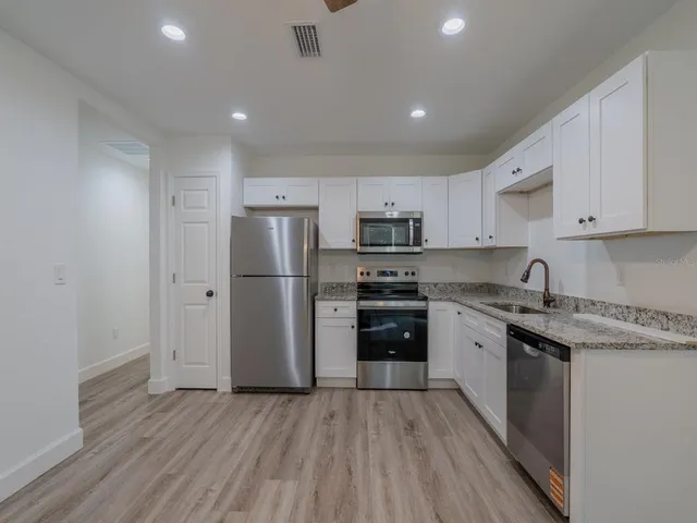 a kitchen with stainless steel appliances granite countertop a refrigerator a stove top oven a sink dishwasher and wooden floor