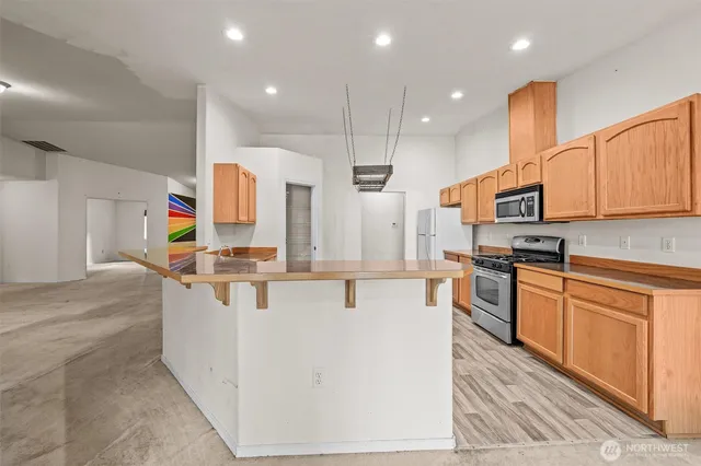 a kitchen with stainless steel appliances kitchen island granite countertop a sink and a refrigerator
