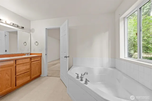 a spacious bathroom with a tub sink and mirror
