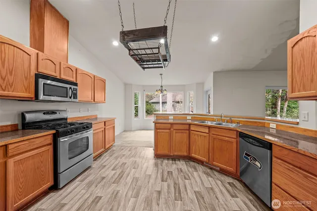 a kitchen with stainless steel appliances granite countertop wooden cabinets granite counter tops and a hard wood floors