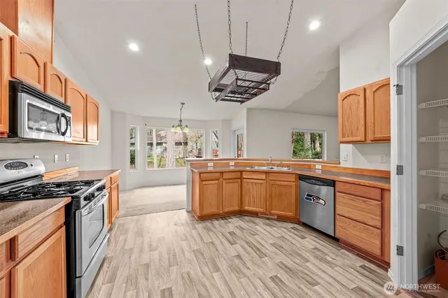 a large kitchen with stainless steel appliances granite countertop a stove and a wooden floors