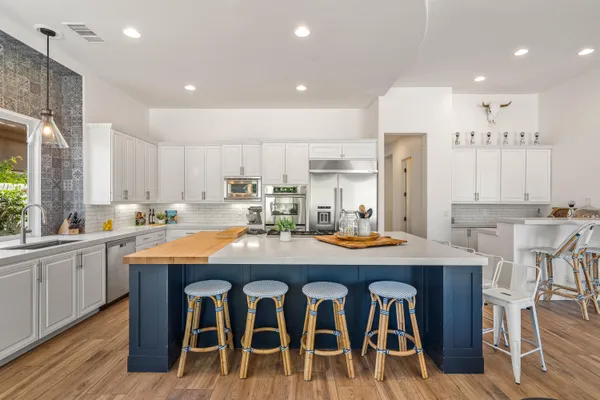 a kitchen with stainless steel appliances granite countertop a table chairs sink and cabinets
