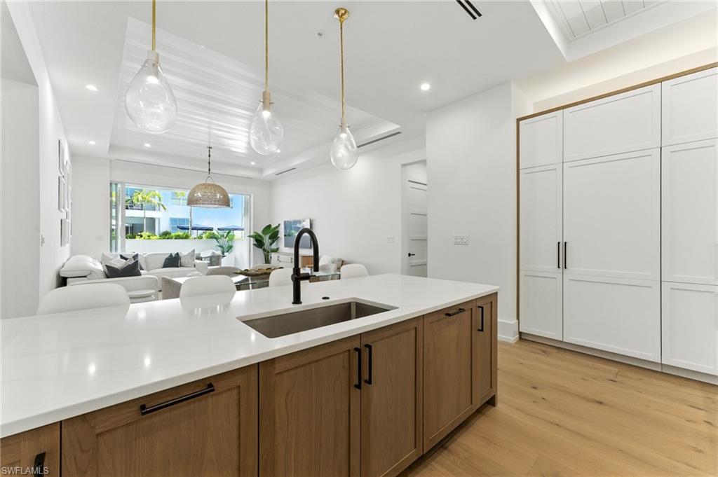 201 8th Street South, Unit 208 Naples, FL 34102 - Photo 11 of 39 Dining room with bar with sink, light wood-style floors, recessed lighting, and a tray ceiling