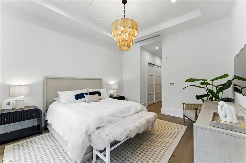 201 8th Street South, Unit 208 Naples, FL 34102 - Photo 15 of 39 Bedroom features a king bed, walkout to patio area, two closets, and en-suite primary bathroom