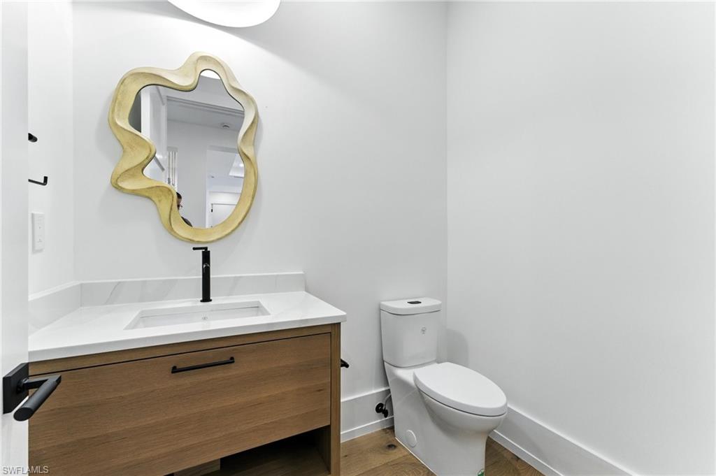 201 8th Street South, Unit 208 Naples, FL 34102 - Photo 38 of 39 Half bath featuring vanity and wood finished floors just off the entry