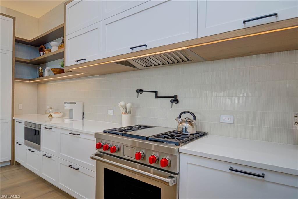 201 8th Street South, Unit 208 Naples, FL 34102 - Photo 10 of 39 Kitchen featuring stainless steel range, backsplash, and light countertops
