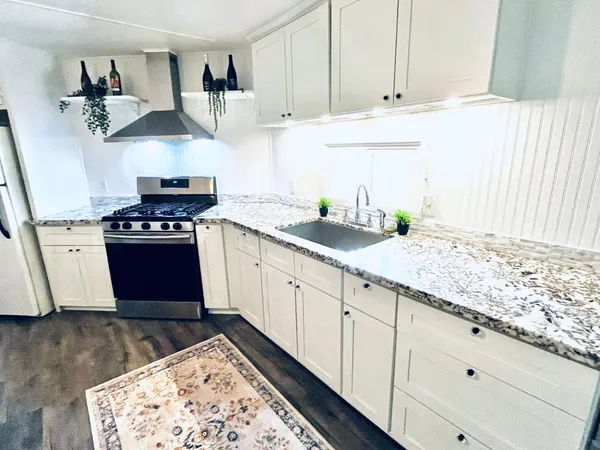 a kitchen with granite countertop a stove a sink and dishwasher wooden cabinets with granite countertops