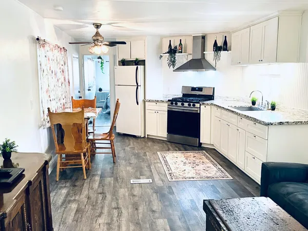 a kitchen with stainless steel appliances granite countertop a stove top oven a sink a dining table and chairs with wooden floor