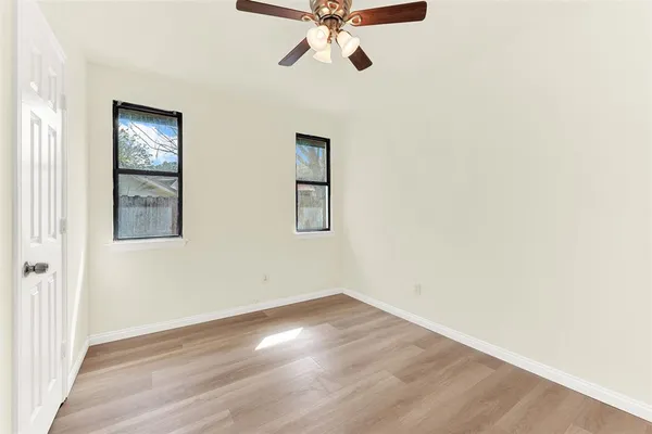 an empty room with a window and a chandelier fan