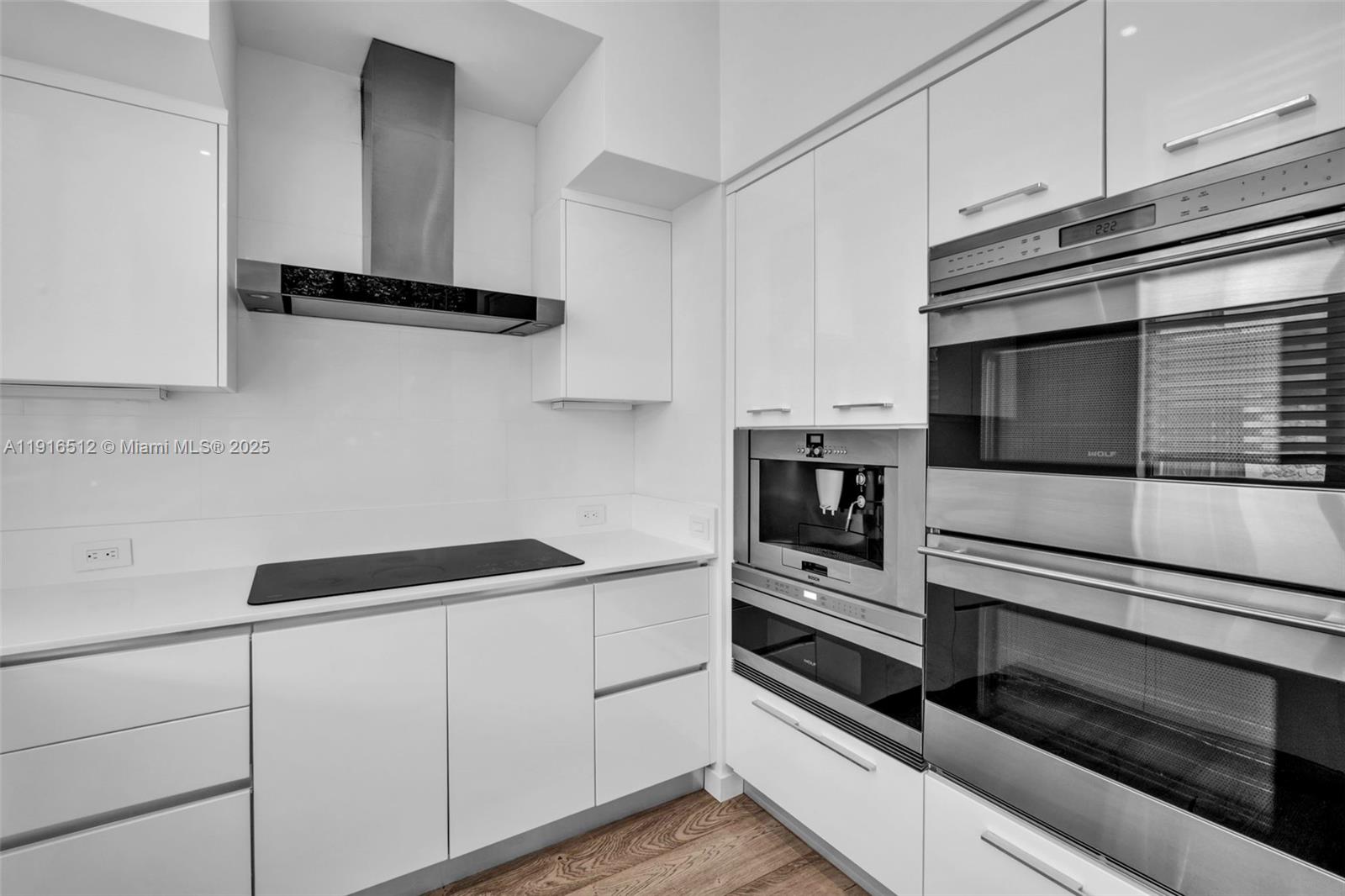 9501 Collins Avenue, Unit 1 Surfside, FL 33154 - Photo 24 of 53 a kitchen with white cabinets and black appliances