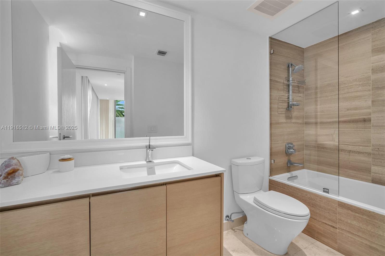 9501 Collins Avenue, Unit 1 Surfside, FL 33154 - Photo 31 of 53 a bathroom with a sink toilet vanity and shower