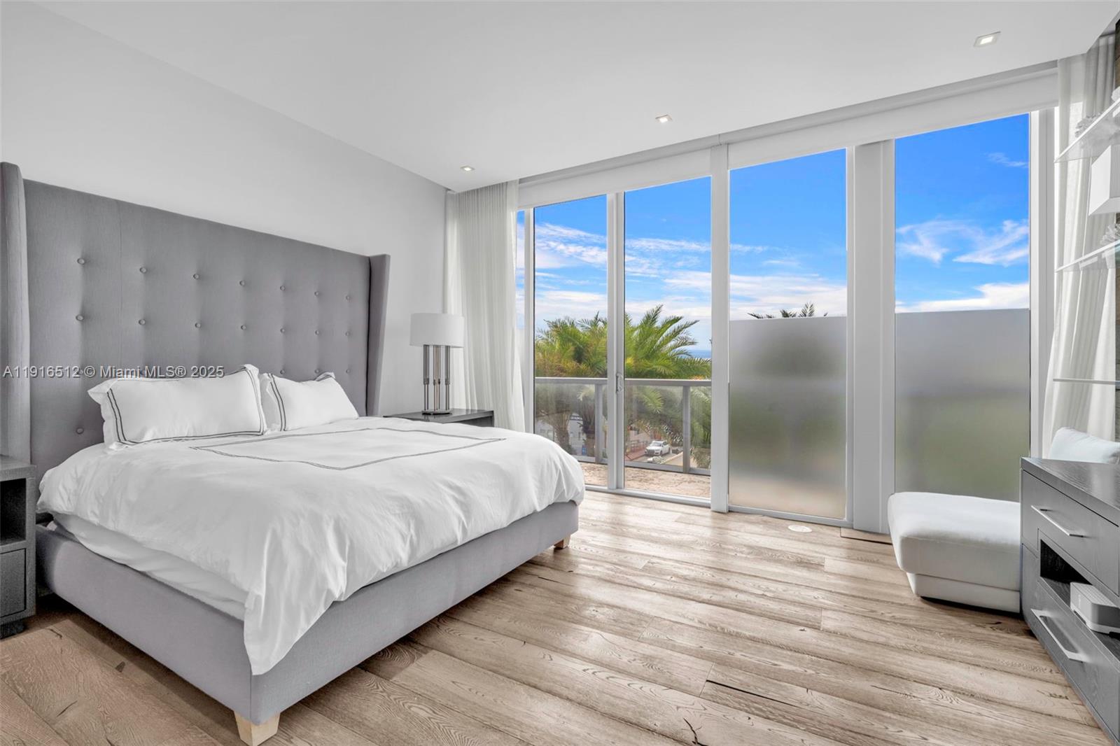 9501 Collins Avenue, Unit 1 Surfside, FL 33154 - Photo 34 of 53 a large bedroom with a bed and glass door