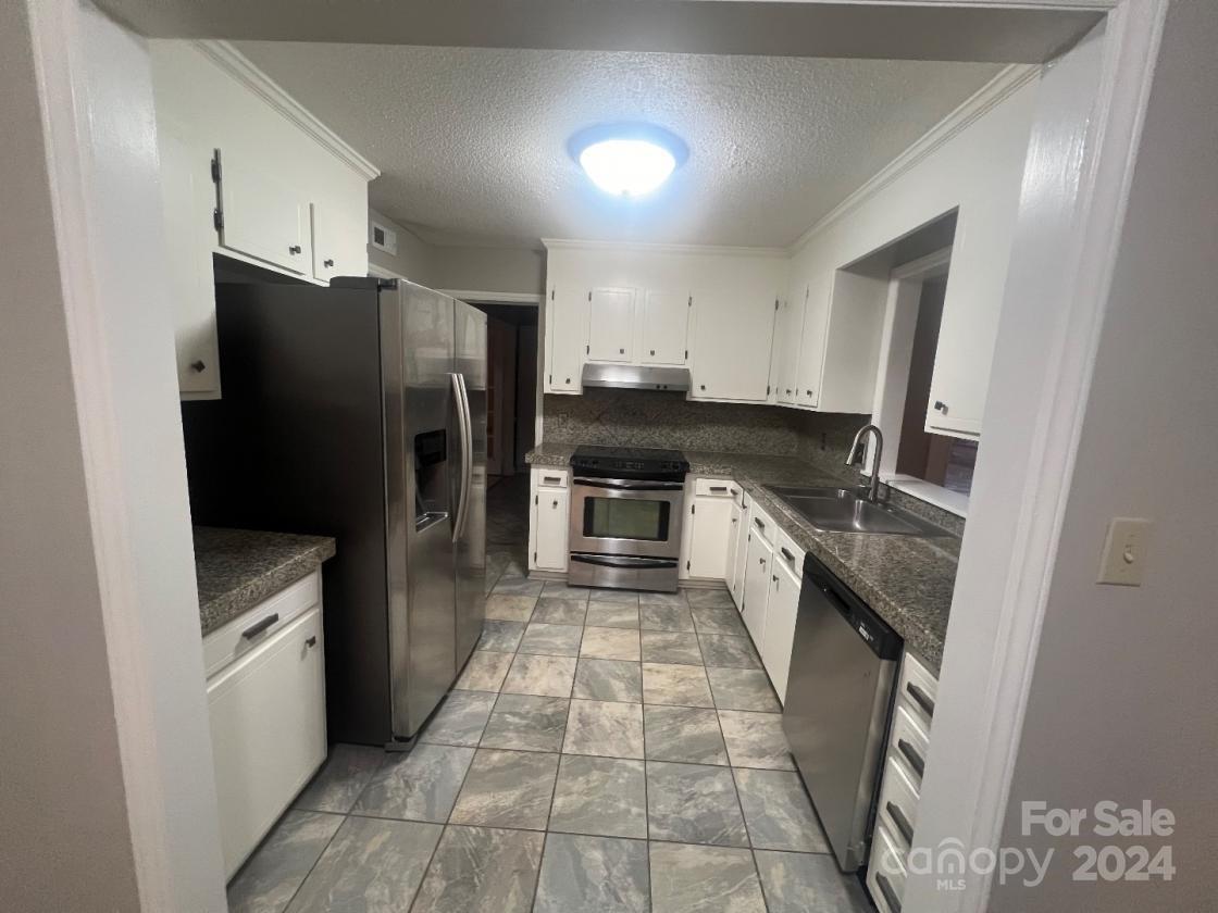 11714 Harrowfield Road Charlotte, NC 28226 - Photo 3 of 15 a kitchen with granite countertop a refrigerator and a stove