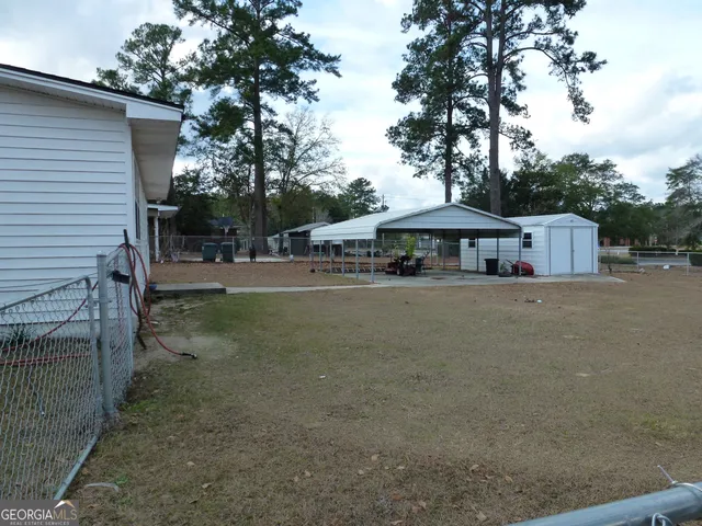 a backyard of a house with table and chairs under an umbrella