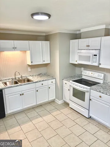 a kitchen with granite countertop white cabinets and white appliances