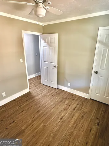 an empty room with wooden floor and ceiling fan