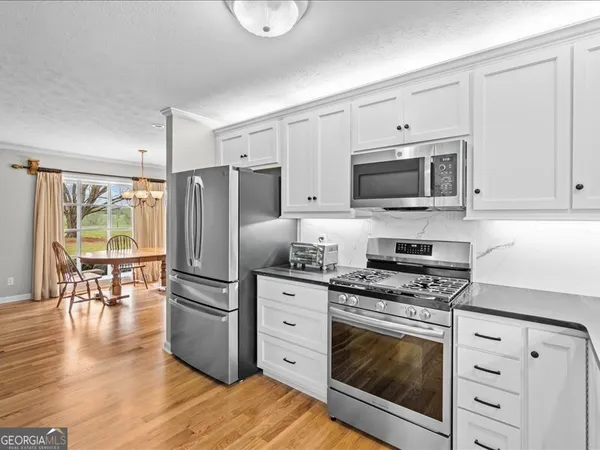 a kitchen with granite countertop a refrigerator stove and white cabinets