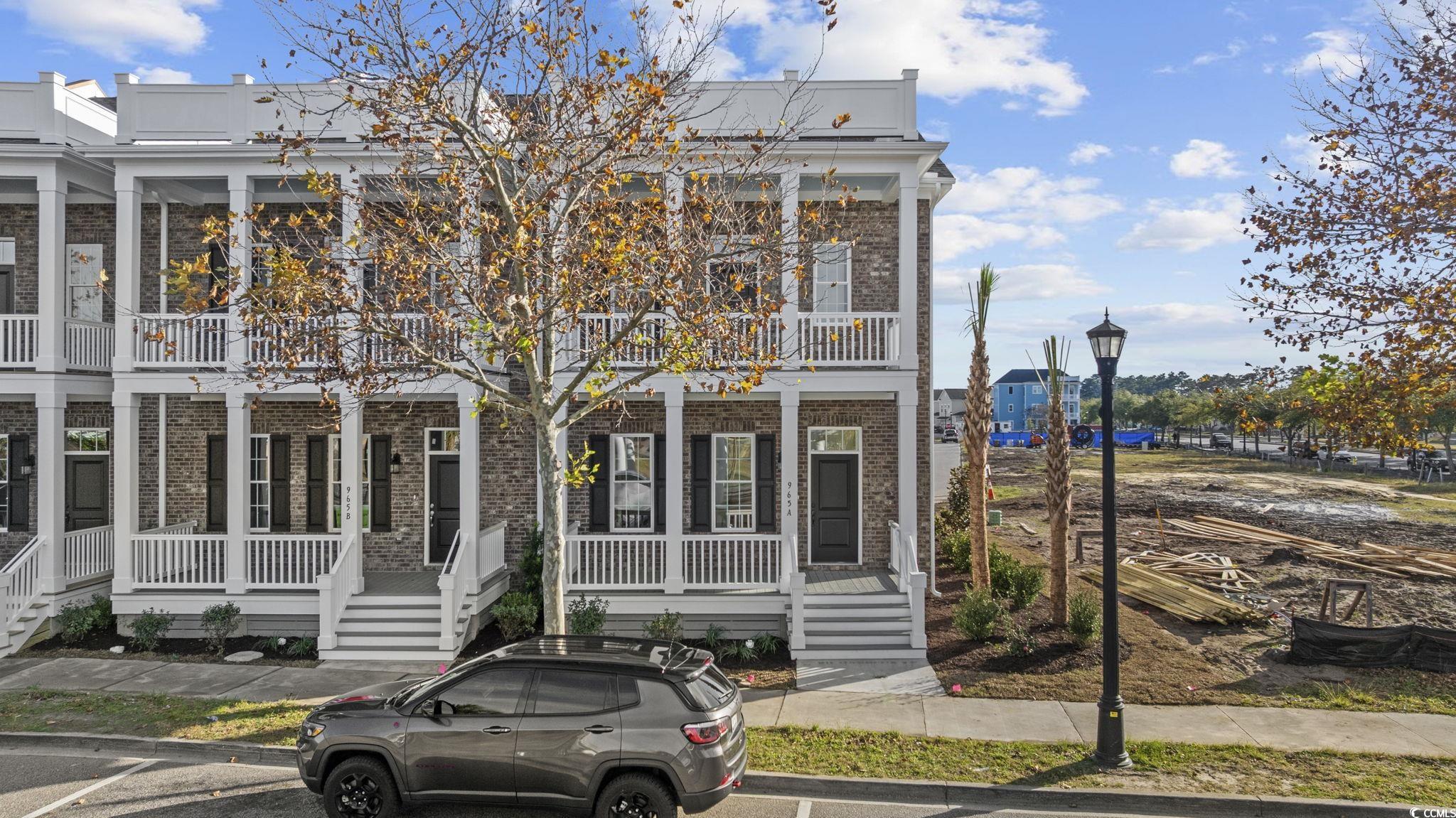 Neoclassical / greek revival house with brick siding, a porch, and a balcony