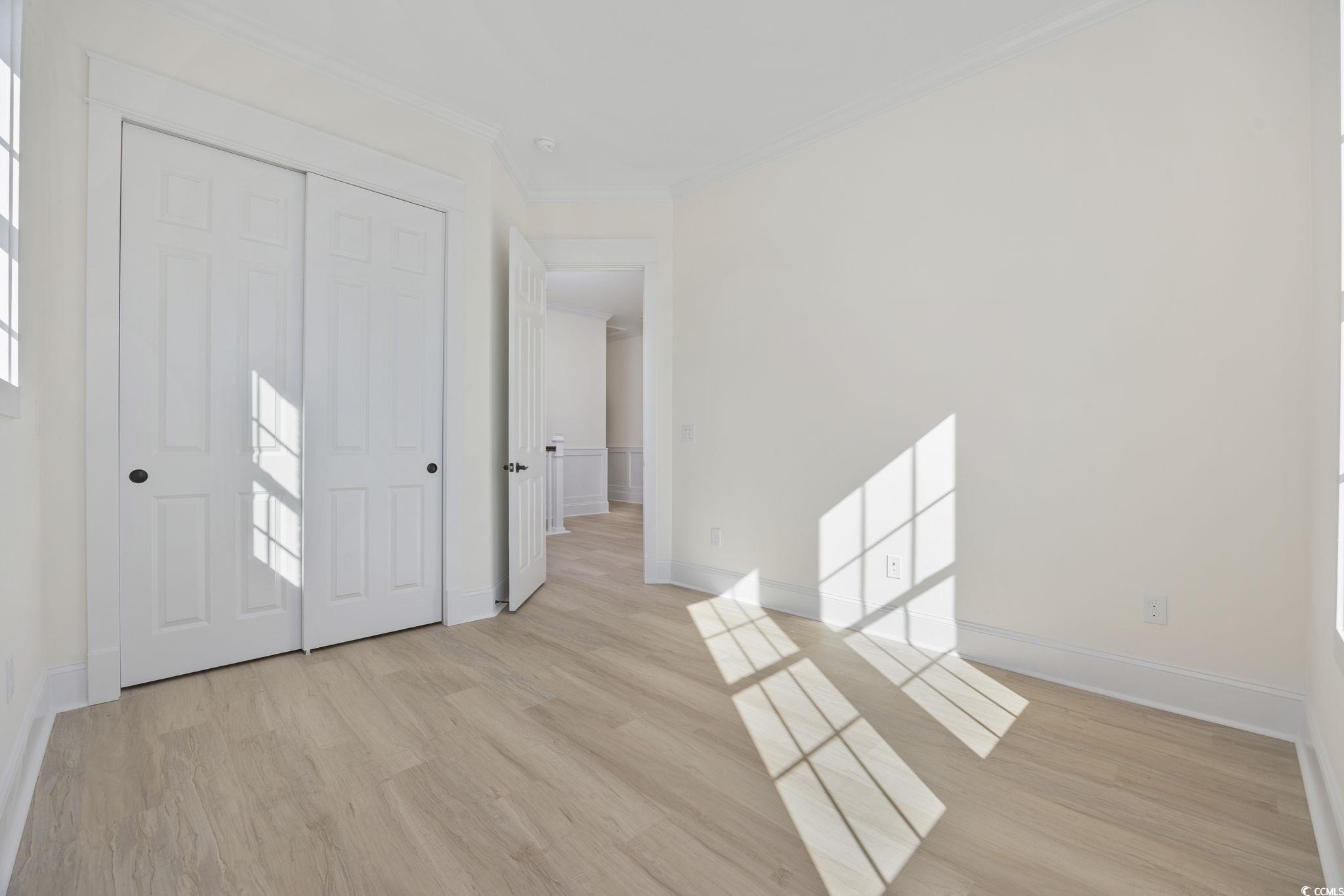 965 Hackler Street, Unit E Myrtle Beach, SC 29577 - Photo 20 of 36 Unfurnished bedroom featuring light wood-style flooring, crown molding, and a closet