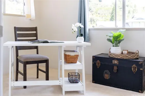 a living room with a table chairs and potted plant