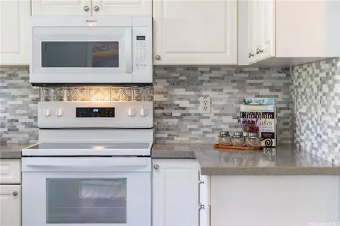 a kitchen with granite countertop white cabinets and stainless steel appliances