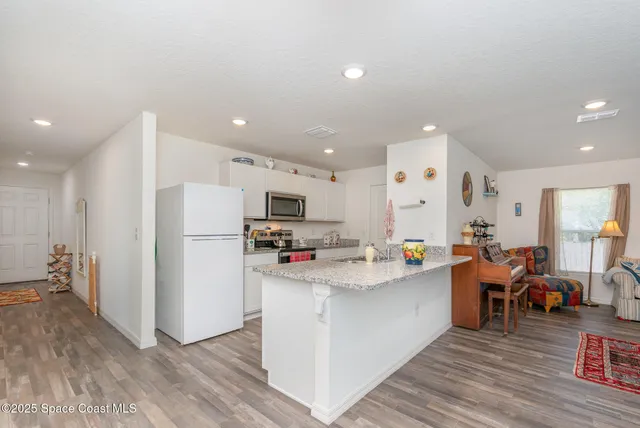 a view of kitchen with stainless steel appliances lots of counter space and wooden floor