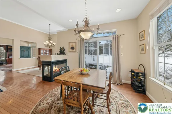 a dining room with wooden floor a chandelier a wooden table and chairs