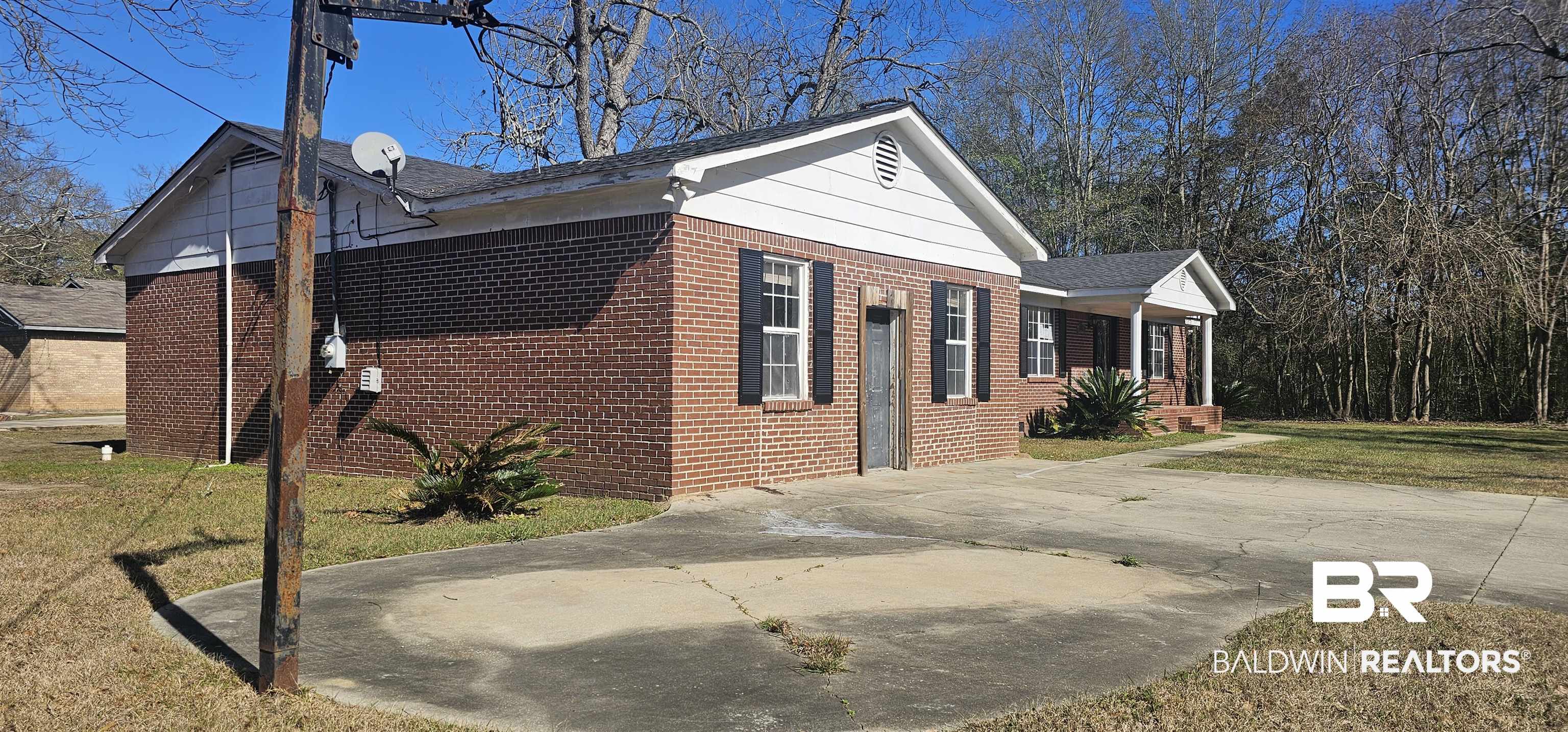 151 Bullard Street Atmore, AL 36502 - Photo 38 of 38 View of side of home with brick siding, a lawn, a porch, and driveway