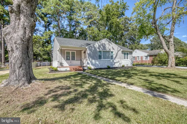 a view of a house with a small yard and large tree