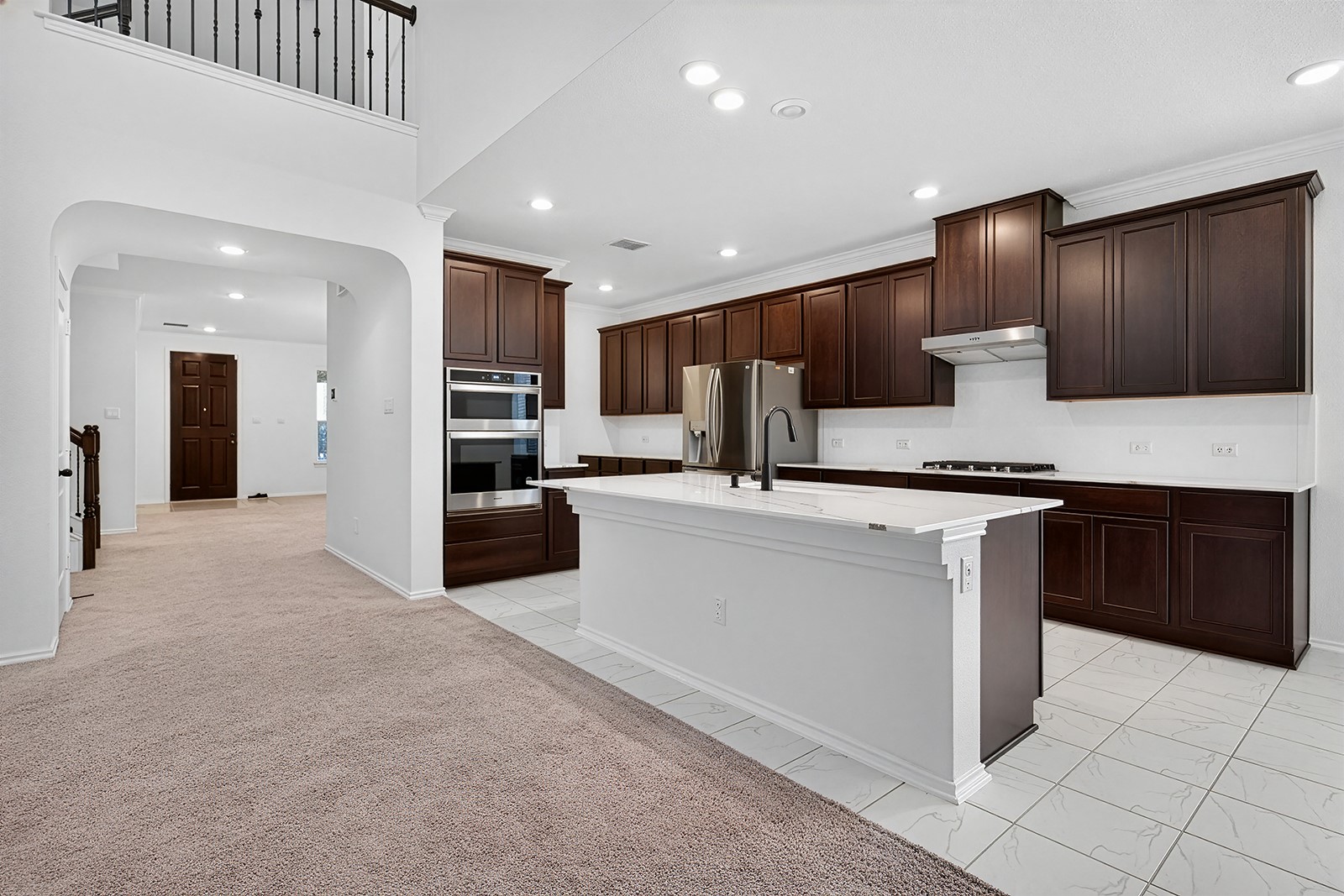 4600 Ercolano Lane Round Rock, TX 78665 - Photo 19 of 37 Spacious kitchen featuring dark wood cabinetry, white countertops, built-in stainless steel appliances, a center island with a sink, and recessed lighting