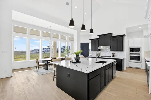 a open kitchen with stainless steel appliances granite countertop a stove top oven a sink dishwasher and a table with chairs