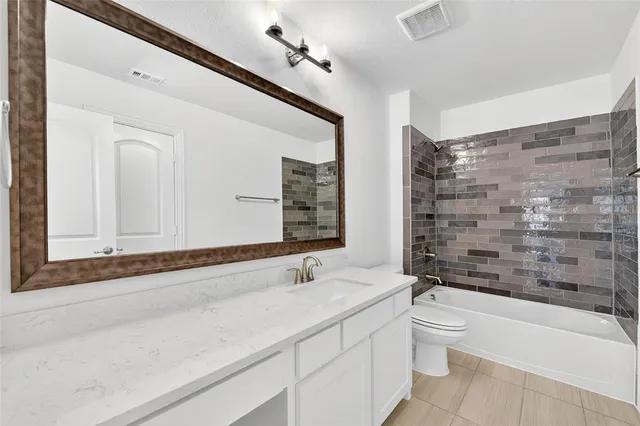a bathroom with a granite countertop sink a toilet and bathtub