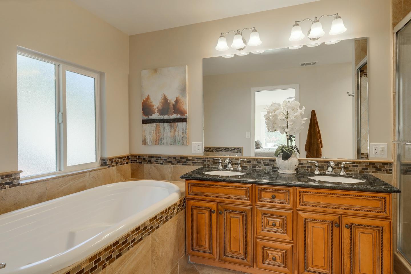22620 Ricardo Road Cupertino, CA 95014 - Photo 15 of 34 a bathroom with a granite countertop sink a large mirror and a bathtub next to a window