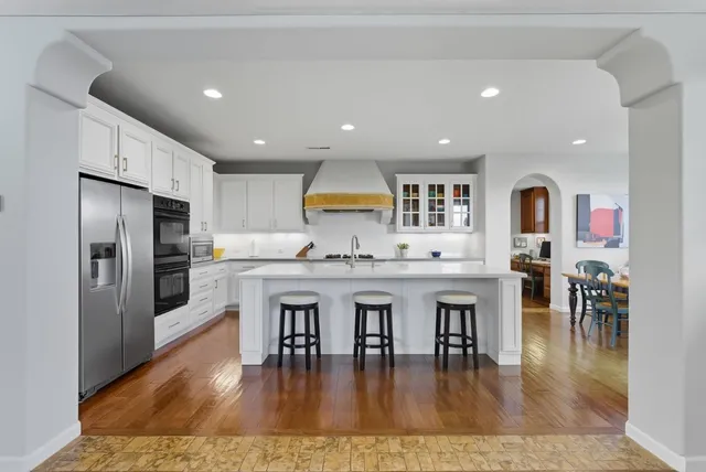 a open kitchen with stainless steel appliances granite countertop a stove refrigerator and a dining table with wooden floor