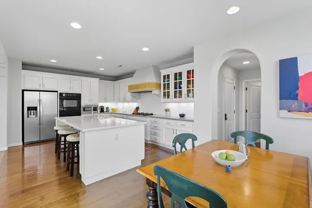 a kitchen with stainless steel appliances granite countertop a kitchen island a stove a table and chairs