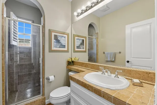 a bathroom with a granite countertop sink toilet a mirror and shower