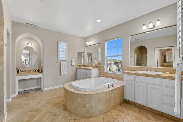 a spacious bathroom with a tub sink and mirror