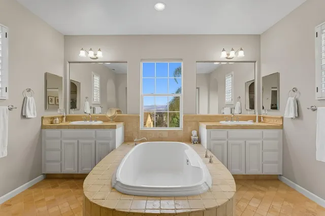 a bathroom with a double vanity sink mirror and bathtub