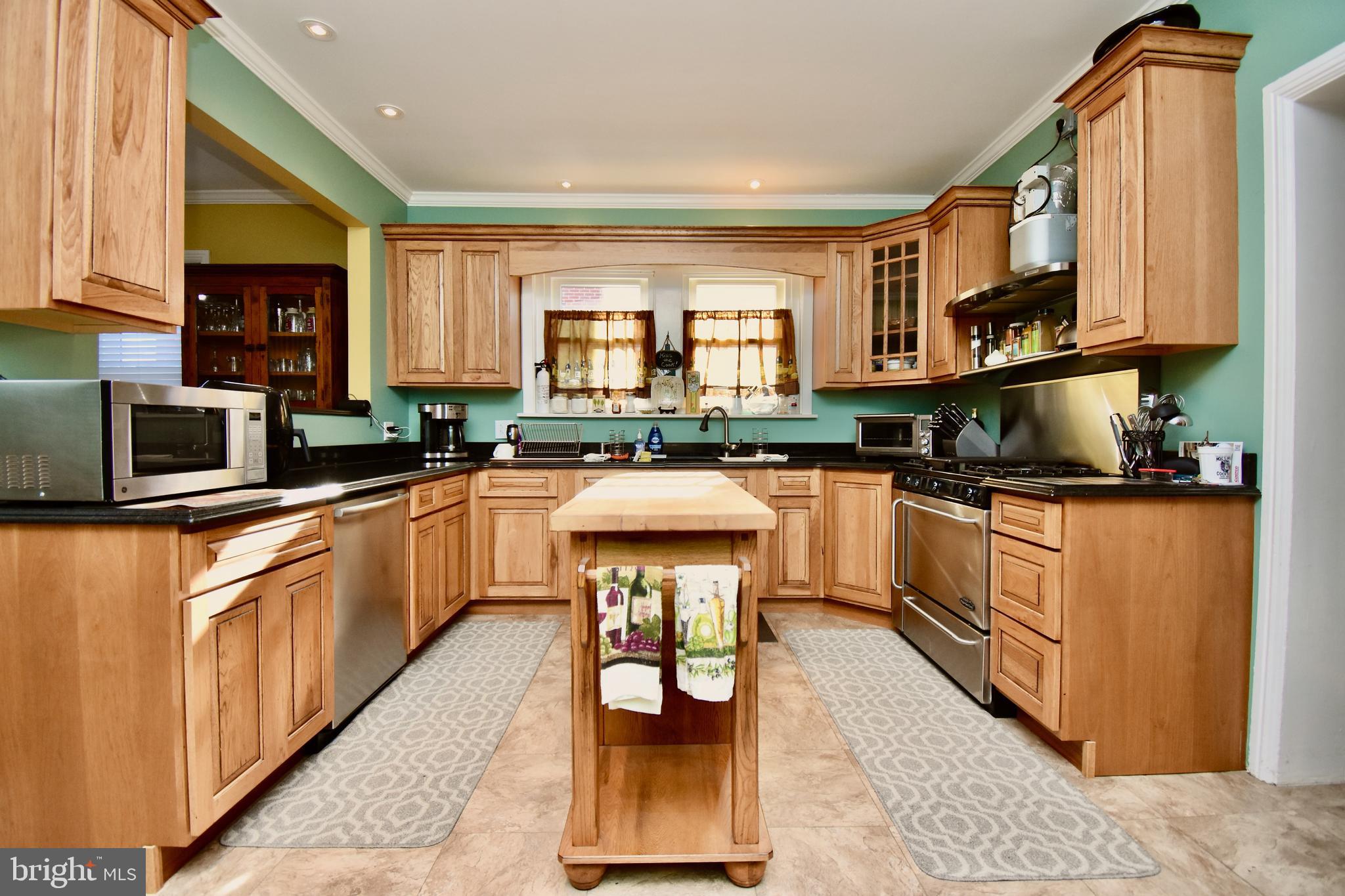 a kitchen with stainless steel appliances granite countertop a stove top oven a sink a counter space and cabinets