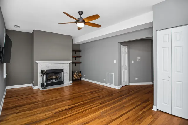 an empty room with wooden floor a ceiling fan and a fireplace