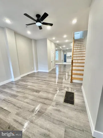 a view of an empty room with wooden floor and a ceiling fan