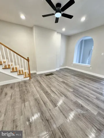 an empty room with wooden floor windows and a ceiling fan