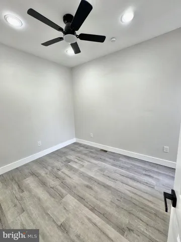 an empty room with a ceiling fan and wooden floor