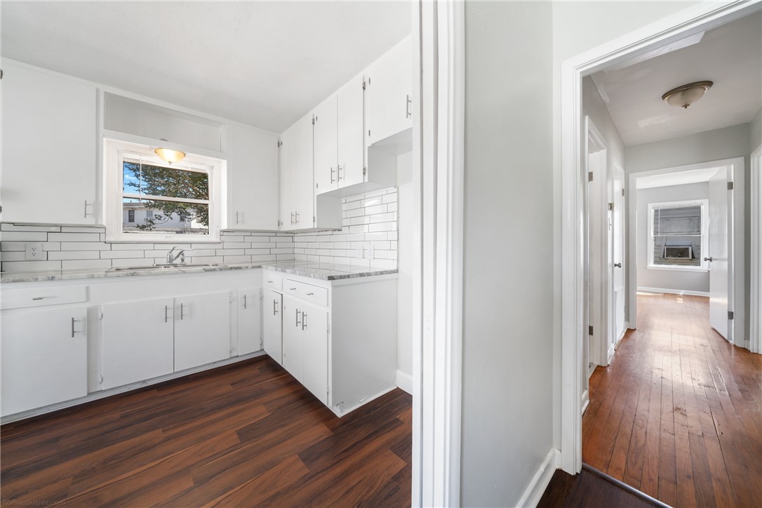 826 Rosedale Drive Corpus Christi, TX 78411 - Photo 12 of 22 a kitchen with wooden floors and white cabinets