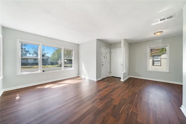 a view of empty room with wooden floor and fan