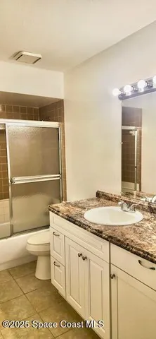 a bathroom with a granite countertop sink mirror vanity and toilet
