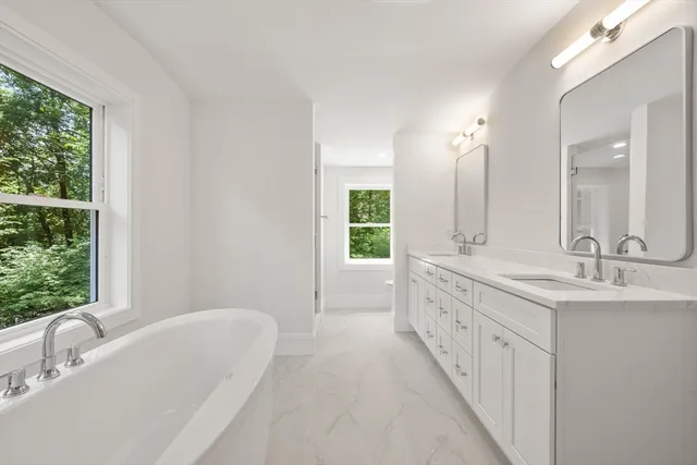 a spacious bathroom with a double vanity sink a mirror and a bathtub