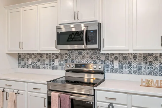 a kitchen with a stove and white cabinets