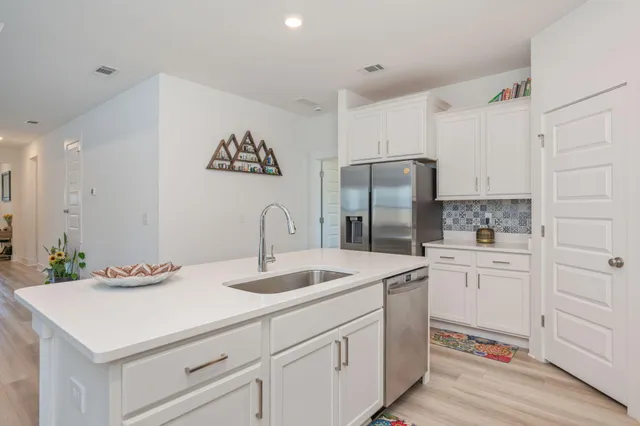 a kitchen that has a lot of white cabinets and stainless steel appliances