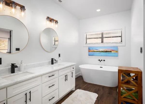 a spacious bathroom with a double vanity sink mirror and bathtub